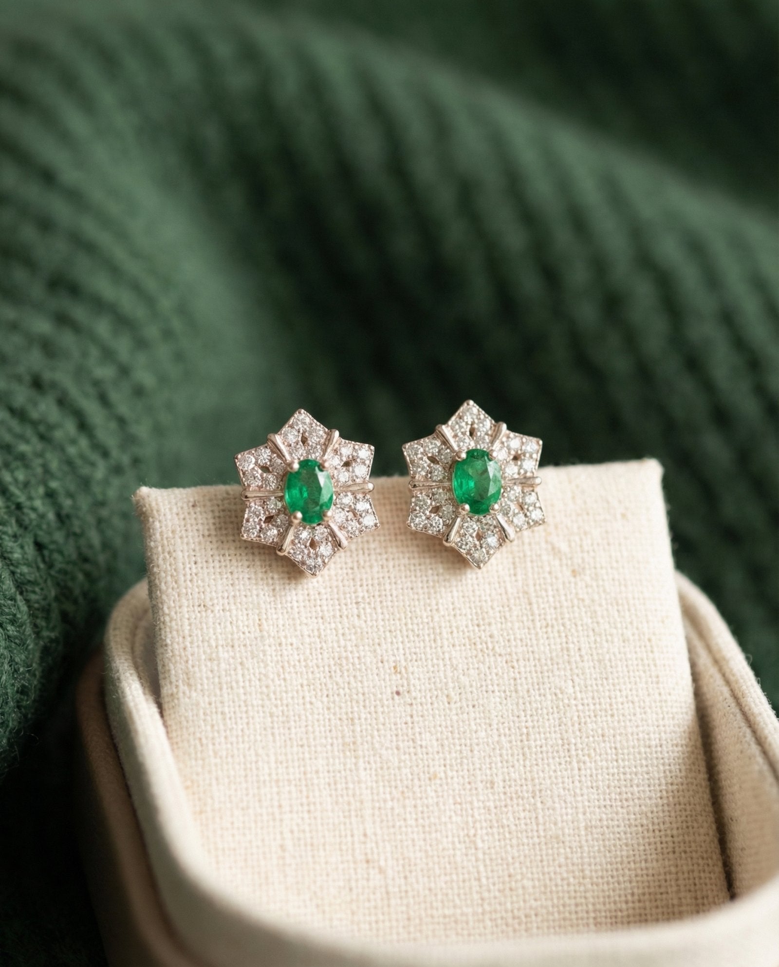 Pair of silver Emerald Starflower Studs displayed in a luxury cream linen jewelry box with a deep green background.