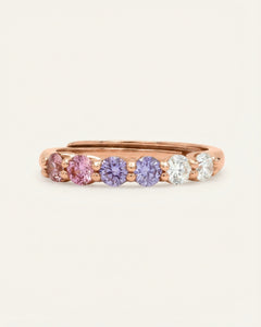 Close-up of the Entwine Eternity Band | Cotton Candy, Elate in rose gold, resting on a warm linen background