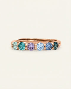 Close-up of the Entwine Eternity Band | Irises, Elate in rose gold, resting on a warm linen background