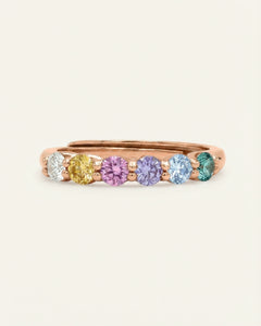Entwine Eternity Band | Pastel Rainbow, Elate in rose gold, resting on a warm linen background