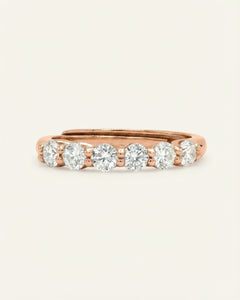 Close-up of the Entwine Eternity Band | White, Elate in rose gold, resting on a warm linen background