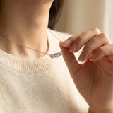 A model wearing the Everglow Trilogy Moissanite Necklace in silver, paired with a cream sweater for a clean, minimalist look.