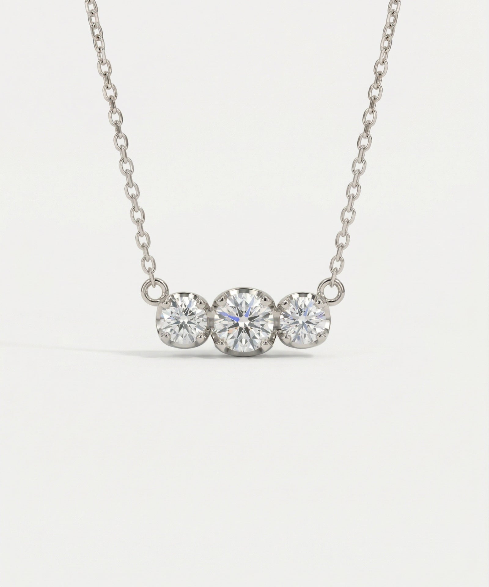 Product image of the Everglow Trilogy Moissanite Necklace in silver, highlighting the D-color VVS1 clarity of the stones.
