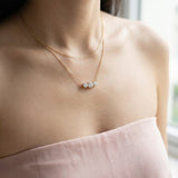 Close-up of a model wearing the Everglow Trilogy Moissanite Necklace in yellow gold, layered with a simple gold chain.