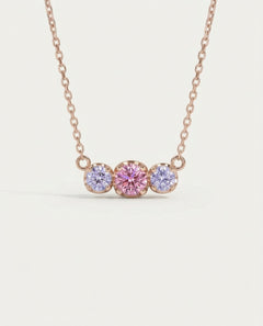 Front-facing product shot of the rose gold Everglow Trilogy Moissanite Necklace, highlighting the Cotton Candy pink and lilac stones.