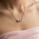 Macro view of the Silver Everglow Trilogy Necklace on a model, showcasing the pastel colorful moissanite sparkle.