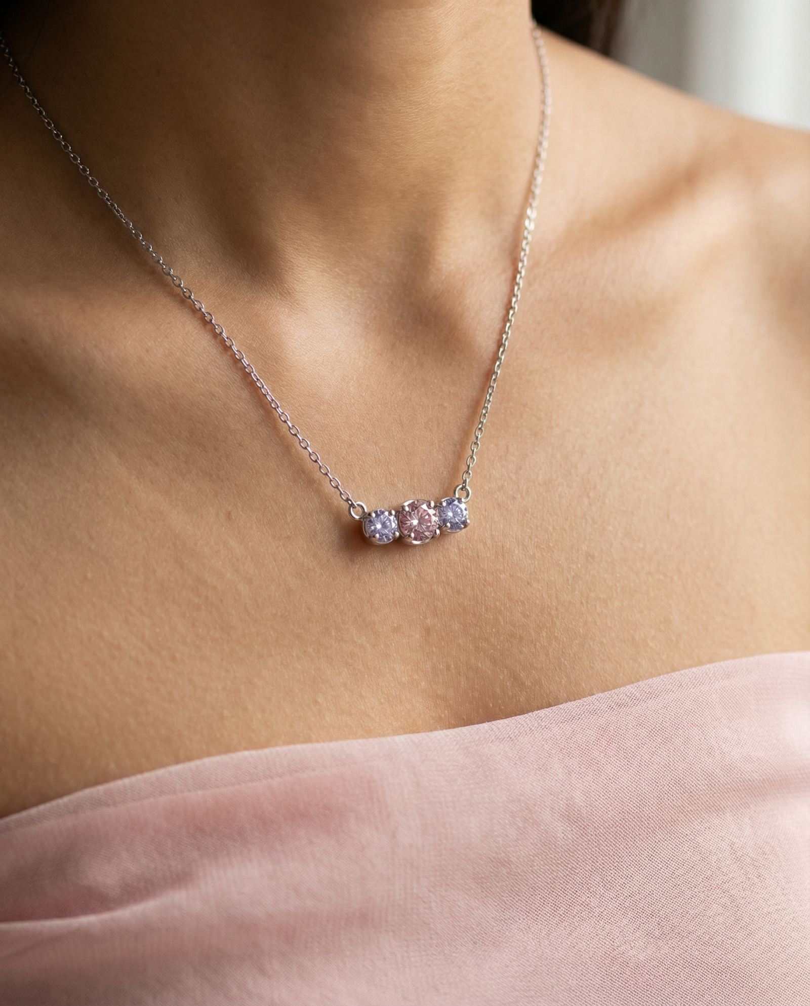Macro view of the Silver Everglow Trilogy Necklace on a model, showcasing the pastel colorful moissanite sparkle.