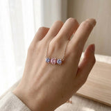 Everglow Trilogy Necklace in silver styled in a luxury cream jewelry box with a blurred soft pink background.