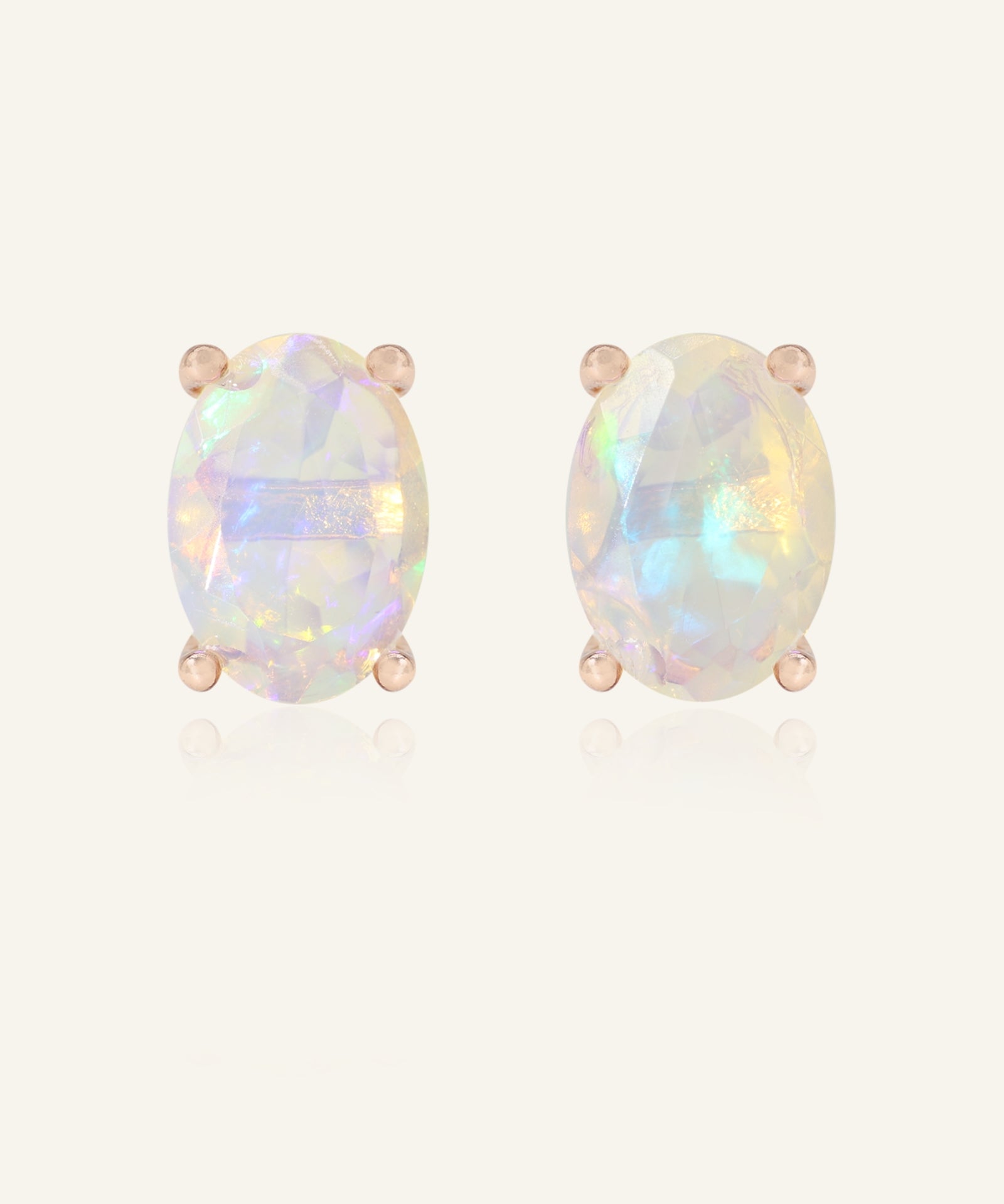 Close-up of the Prism Opal Studs in rose gold, resting on a warm linen background