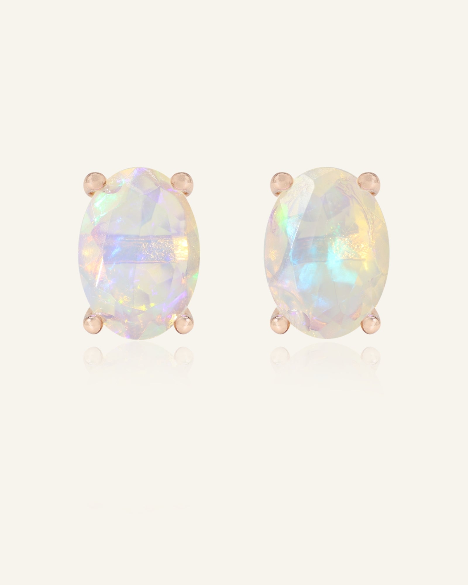 Close-up of the Prism Opal Studs in rose gold, resting on a warm linen background