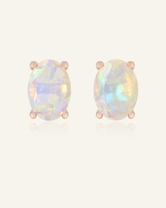Close-up of the Prism Opal Studs in rose gold, resting on a warm linen background