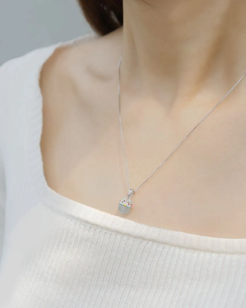 A model wearing the Fortune cat necklace featuring a silver pendant with a cheerful hand-painted cat perched atop a smooth blue chalcedony gemstone, symbolizing serenity and good fortune.