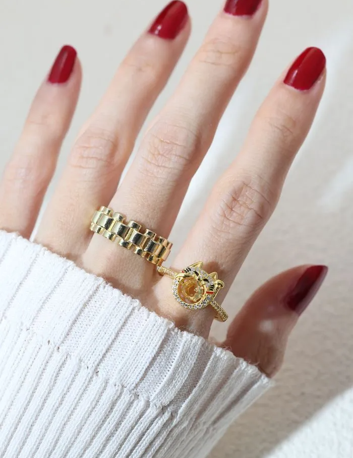 A model wearing the Fortune cat-inspired ring featuring a vibrant citrine gemstone at its center, adorned with shimmering pavé accents and playful enamel details, crafted in yellow gold.
