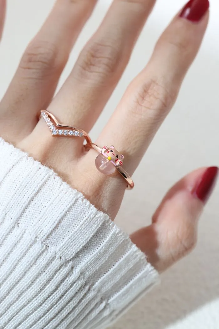 A model wearing the Fortune cat ring crafted in rose gold, featuring a playful cat motif resting on a polished rose quartz gemstone, symbolizing luck and positivity.