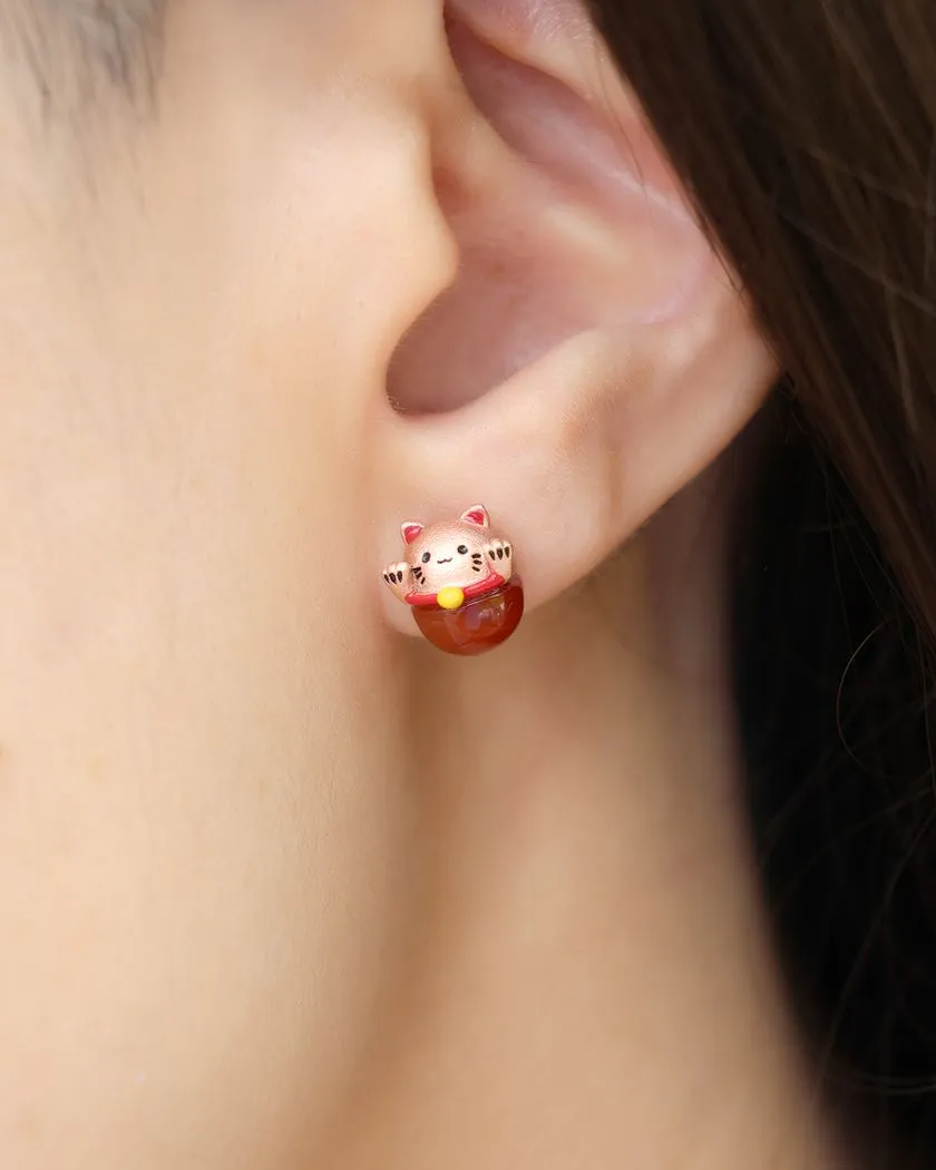Fortune cat studs worn by a model, featuring red agate and rose gold details, designed to bring luck and charm to your look.