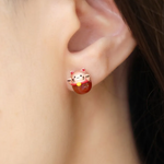 Fortune cat studs worn by a model, featuring red agate and rose gold details, designed to bring luck and charm to your look.