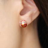 Fortune cat studs worn by a model, featuring red agate and rose gold details, designed to bring luck and charm to your look.