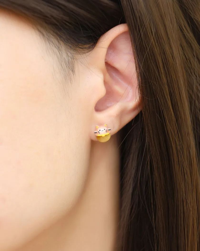 A model wearing the fortune cat-inspired studs featuring adorable feline motifs, elegantly perched on polished tiger eye gemstones for a touch of charm and good fortune.