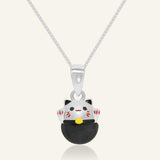Fortune Cat Necklace (Obsidian) in silver, resting on a warm linen background