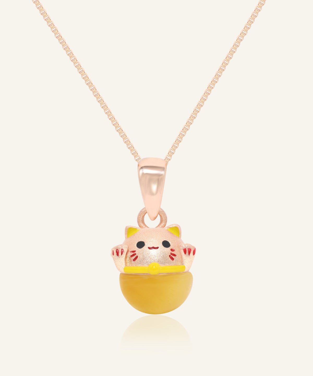 Fortune Cat Necklace (Tiger Eye) in rose gold, resting on a warm linen background
