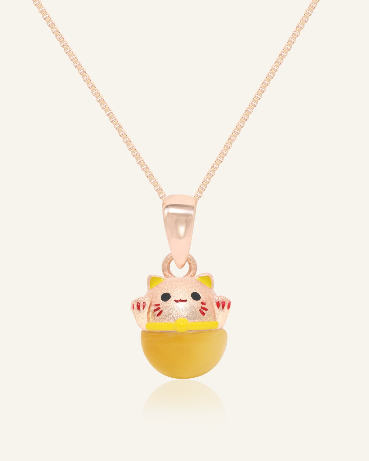 Fortune Cat Necklace (Tiger Eye) in rose gold, resting on a warm linen background