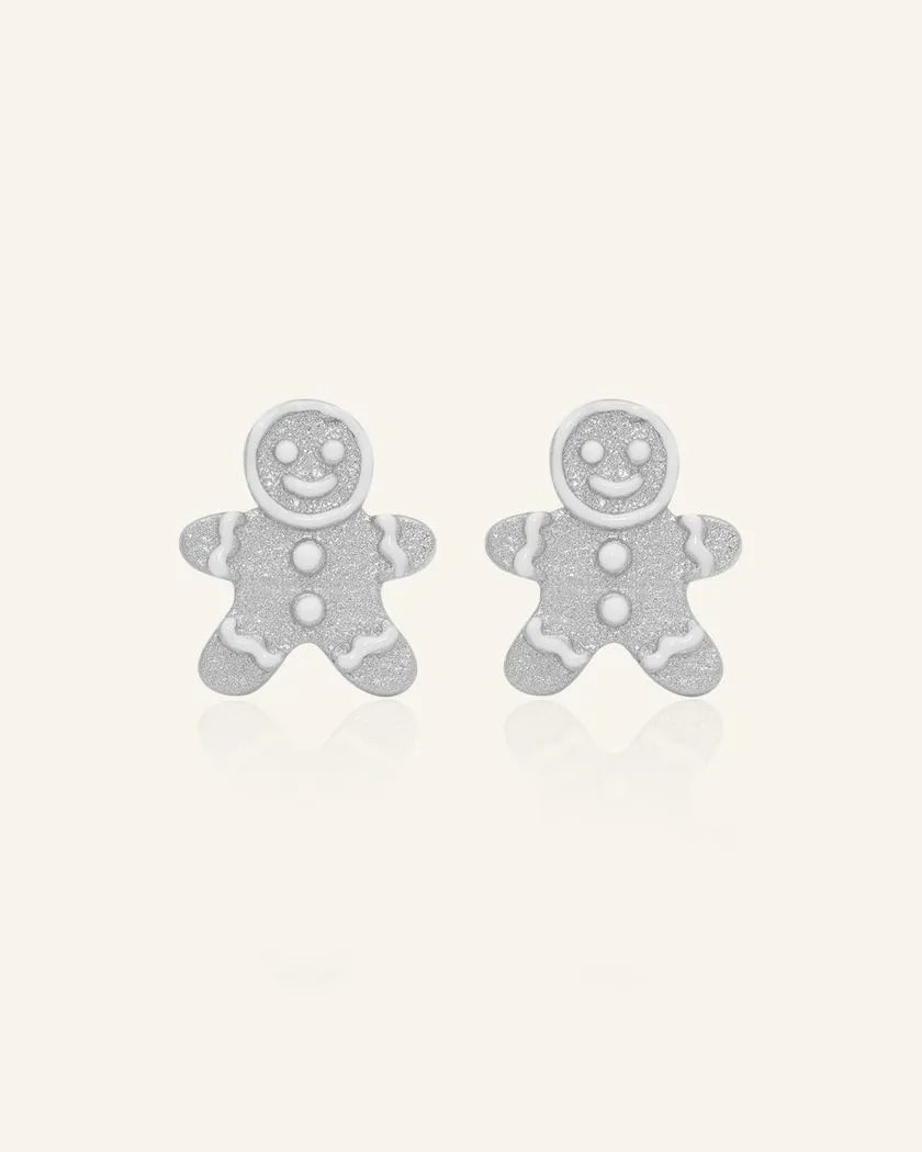 A pair of silver earrings shaped like gingerbread men, adorned with sparkling details and white enamel accents.	