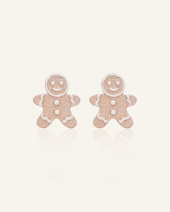 Close-up of the Gingerbread Man Studs in rose gold, resting on a warm linen background