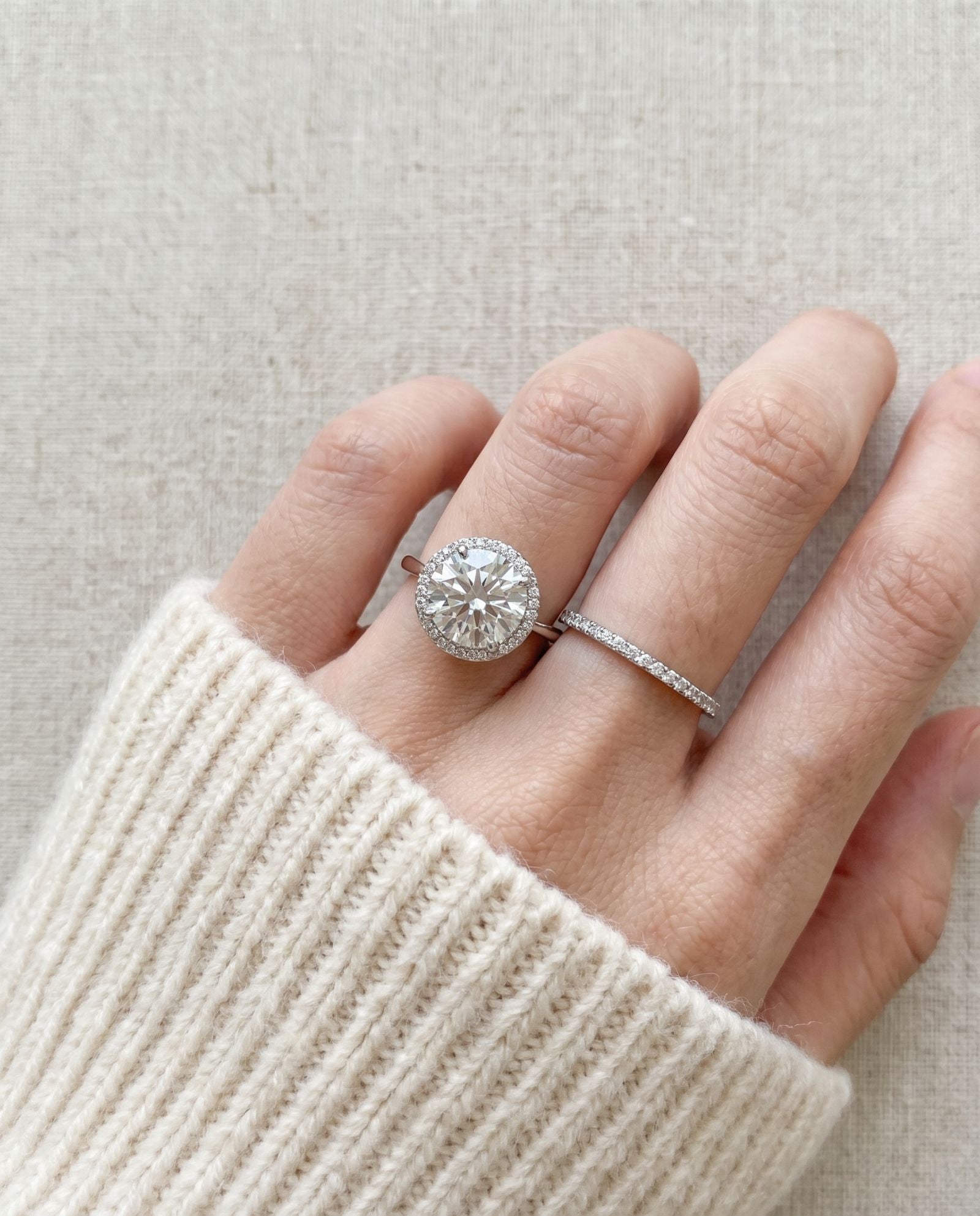 Grand Halo Ring in Silver styled on hand next to a wedding band to show a realistic engagement and anniversary stack.