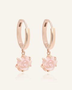 Close-up of the Handcarved Pink Shell Rose Huggies in rose gold, resting on a warm linen background