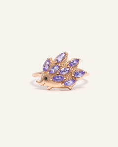 Close-up of the Hedgehog Ring (Tanzanite) in rose gold, resting on a warm linen background