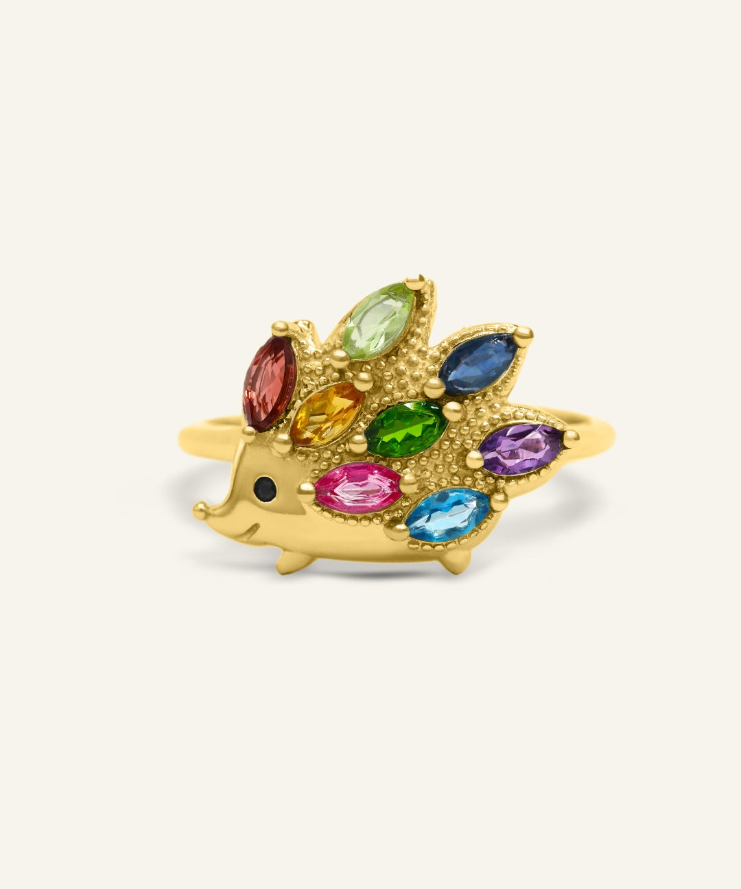 Hedgehog Ring (Multi-Gemstones) in yellow gold, resting on a warm linen background