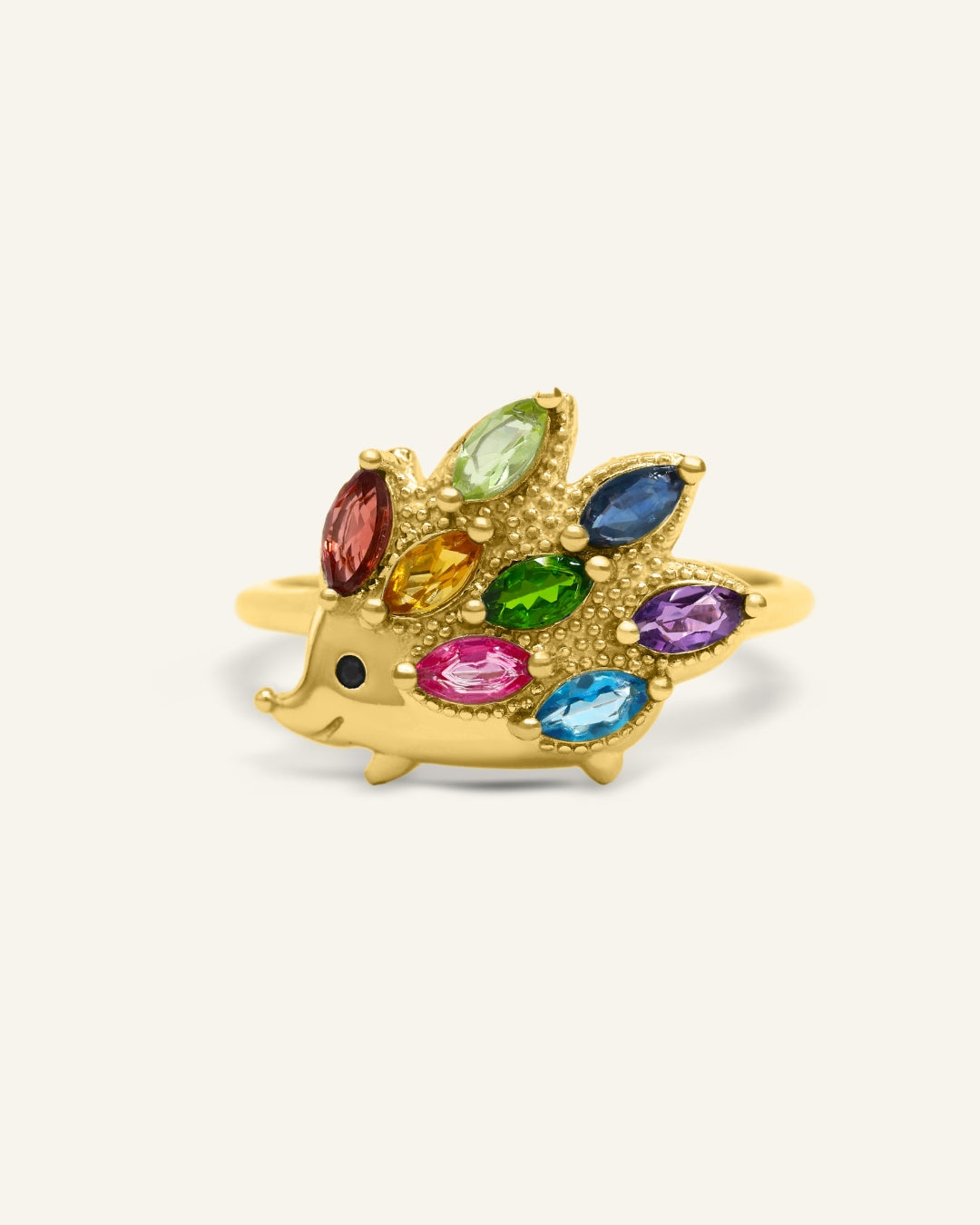 Hedgehog Ring (Multi-Gemstones) in yellow gold, resting on a warm linen background