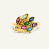 Hedgehog Ring (Multi-Gemstones) in yellow gold, resting on a warm linen background