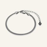 Herringbone Bracelet | Elate in black gold, resting on a warm linen background