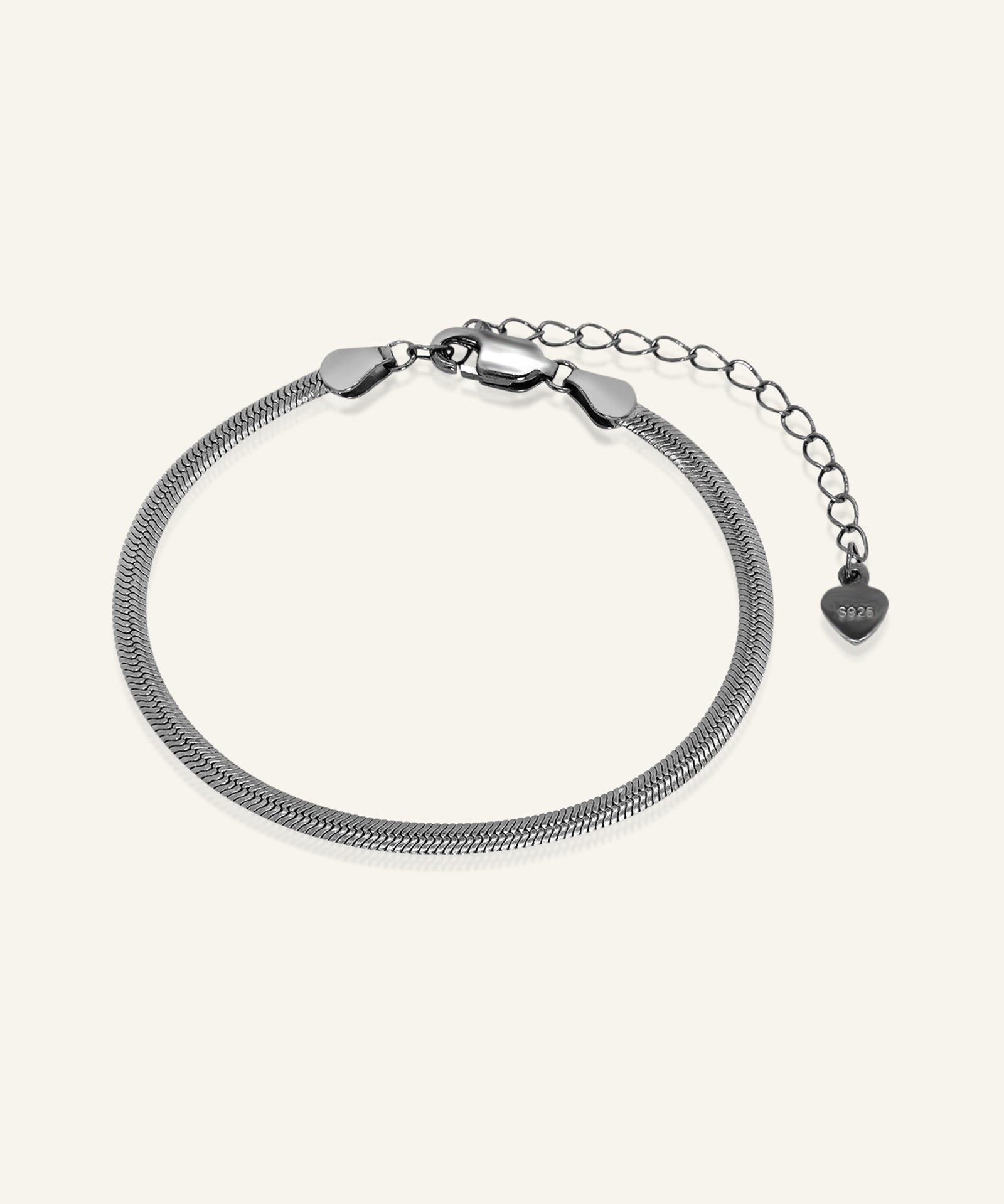 Herringbone Bracelet | Elate in black gold, resting on a warm linen background