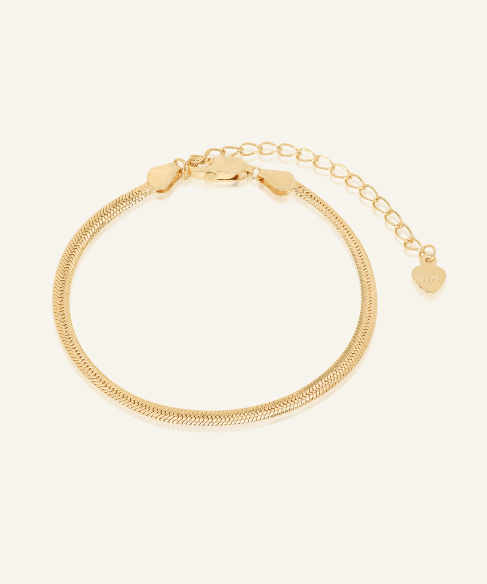 Herringbone Bracelet | Elate in yellow gold, resting on a warm linen background