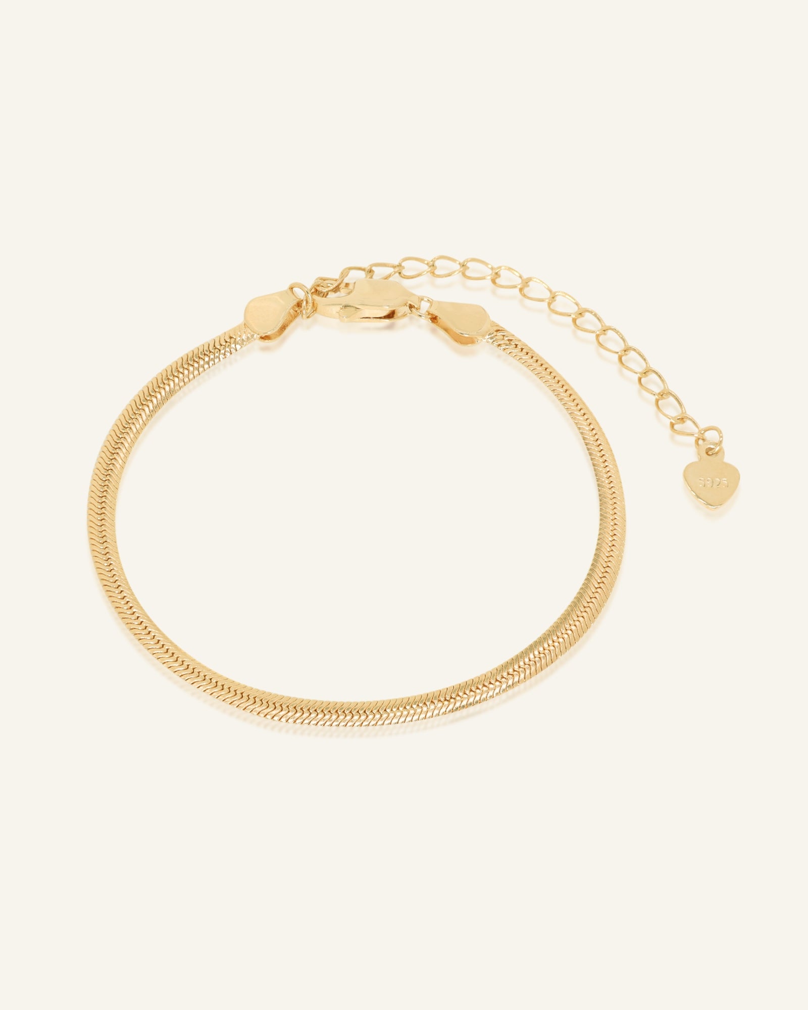 Herringbone Bracelet | Elate in yellow gold, resting on a warm linen background