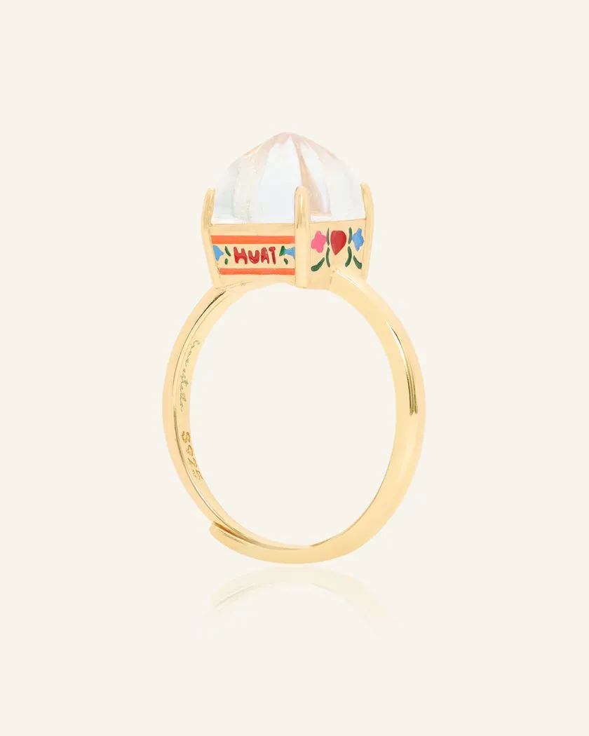 A yellow gold Huat Kueh-inspired ring set with a dome-shaped white topaz centerpiece, featuring intricate hand-painted details of vibrant flowers and the word "HUAT" on the band, symbolizing prosperity and good fortune.