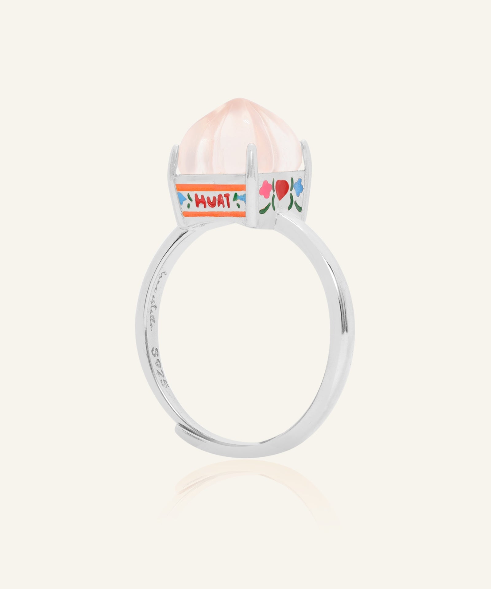 Huat Kueh Ring (Rose Quartz) in yellow gold, resting on a warm linen background