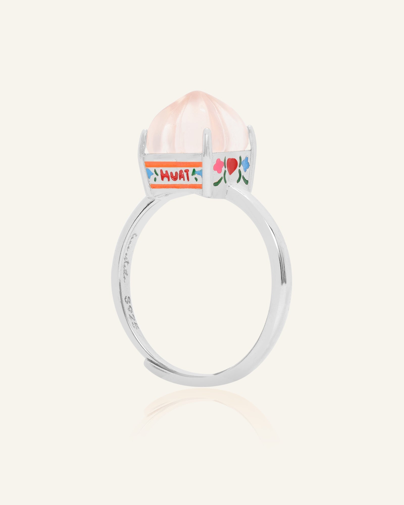 Huat Kueh Ring (Rose Quartz) in yellow gold, resting on a warm linen background