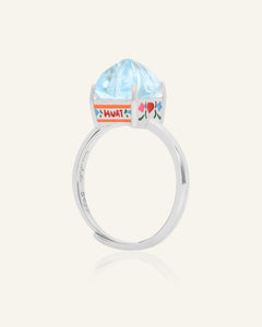 Close-up of the Huat Kueh Ring (Sky Blue Topaz) in silver, resting on a warm linen background