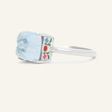 Huat Kueh Ring (Sky Blue Topaz) in silver, resting on a warm linen background, side view