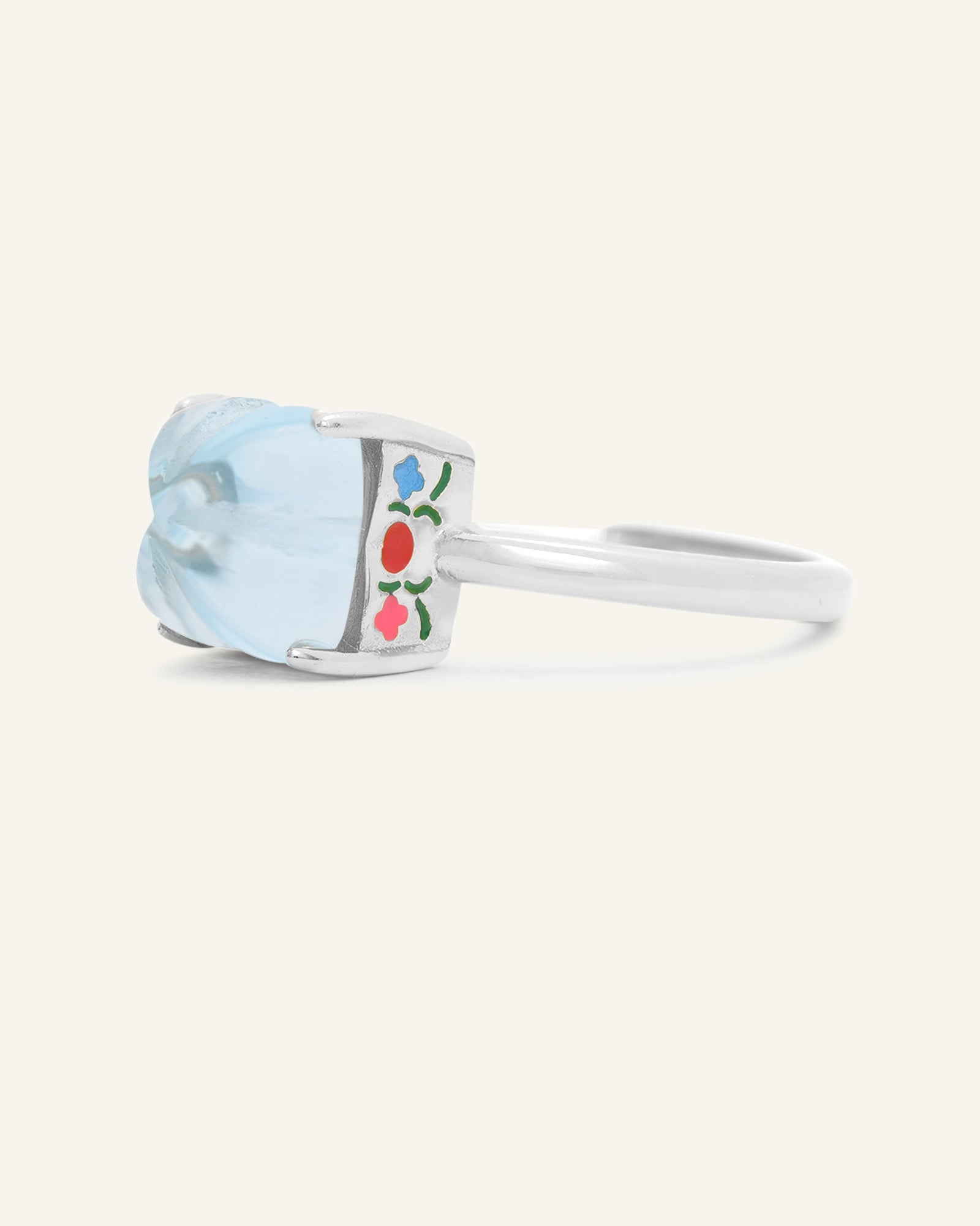Huat Kueh Ring (Sky Blue Topaz) in silver, resting on a warm linen background, side view