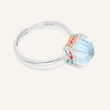 Huat Kueh Ring (Sky Blue Topaz) in silver, resting on a warm linen background, alternate angle
