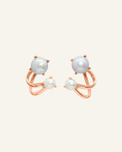 Close-up of the Illusion Ear Jackets | Pearl, Elate in rose gold, resting on a warm linen background
