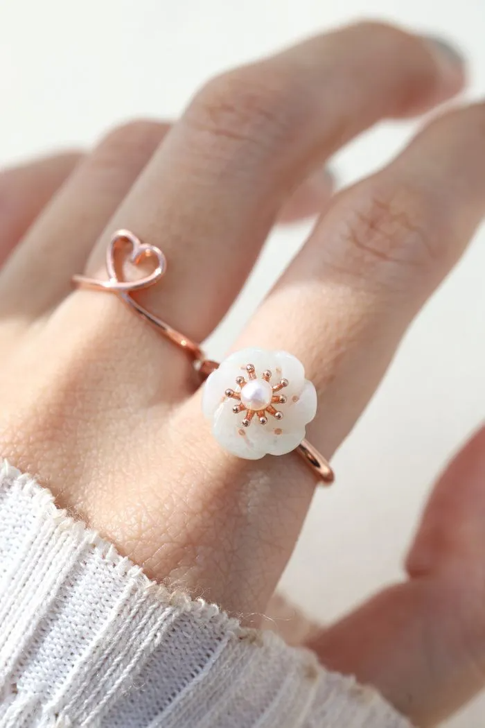 Rose gold jadeite knot ring worn on the finger, highlighting its subtle green hue and intricate knot design.		