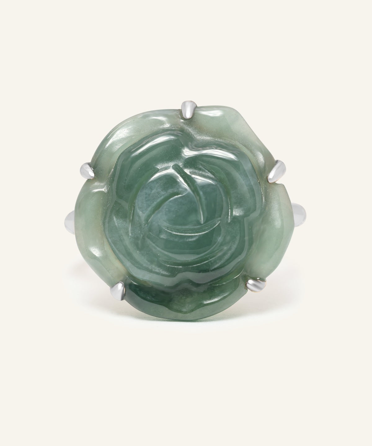 Jadeite Rose Ring in silver, resting on a warm linen background