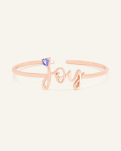 Close-up of the Tanzanite Joy Cuff in rose gold, resting on a warm linen background