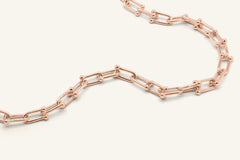 Lock Link Necklace in rose gold, resting on a warm linen background