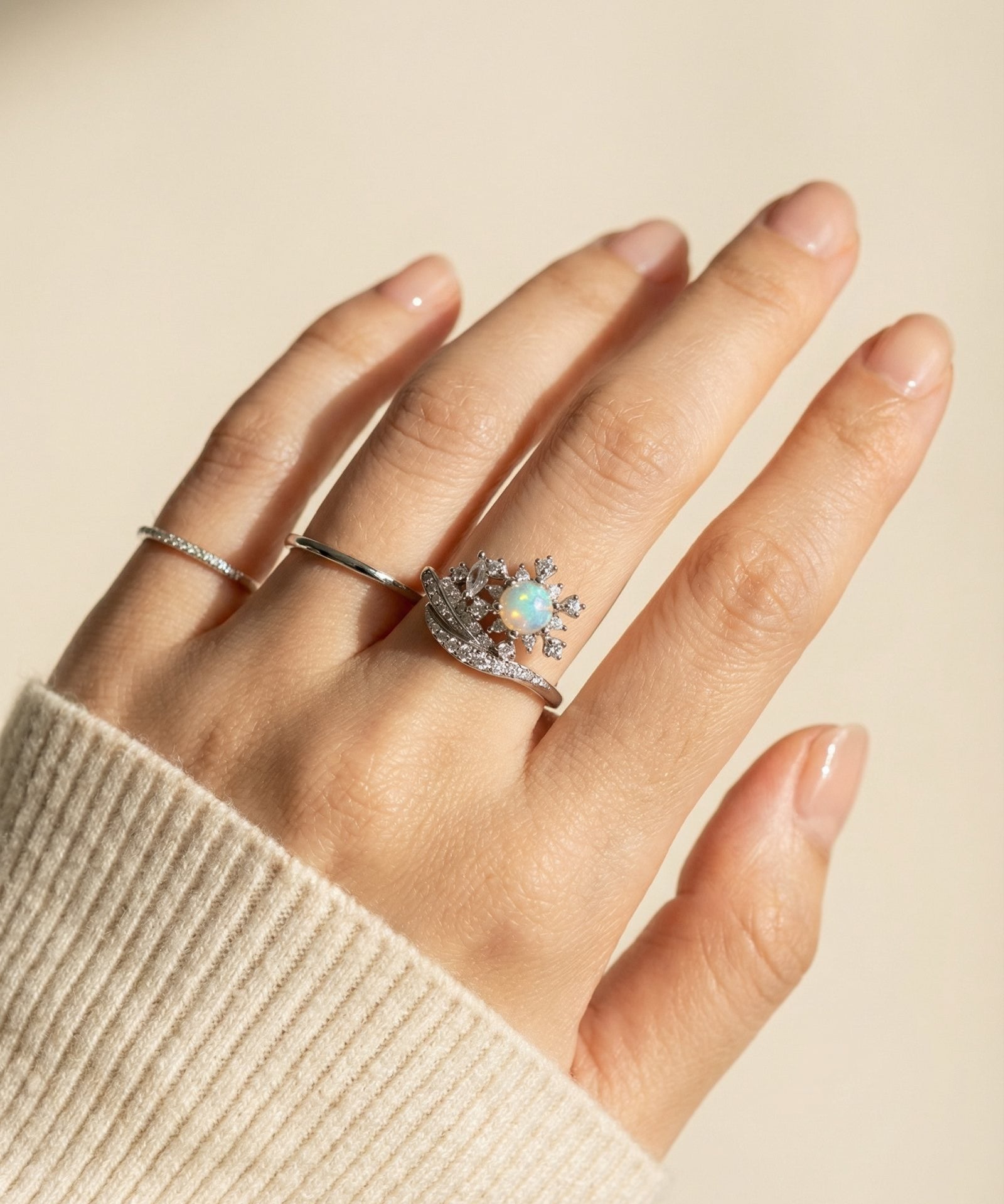 Hand wearing the Silver Lumina Opal Star Ring styled with a minimalist band and cozy knit sweater.
